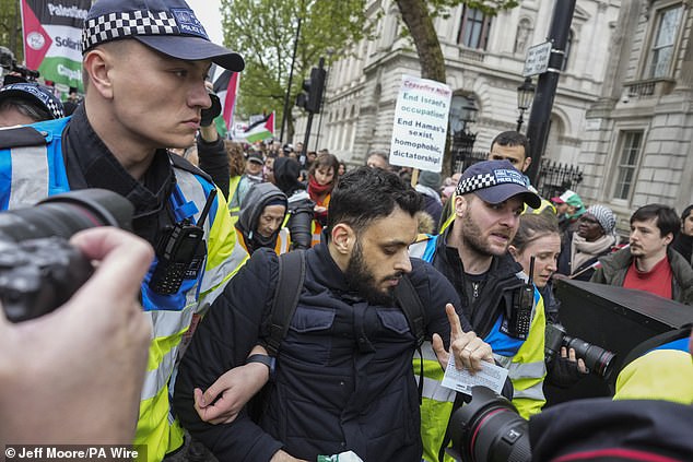 Agentes de policía detienen a una persona mientras la gente participa en una marcha pro Palestina en Whitehall, en el centro de Londres.