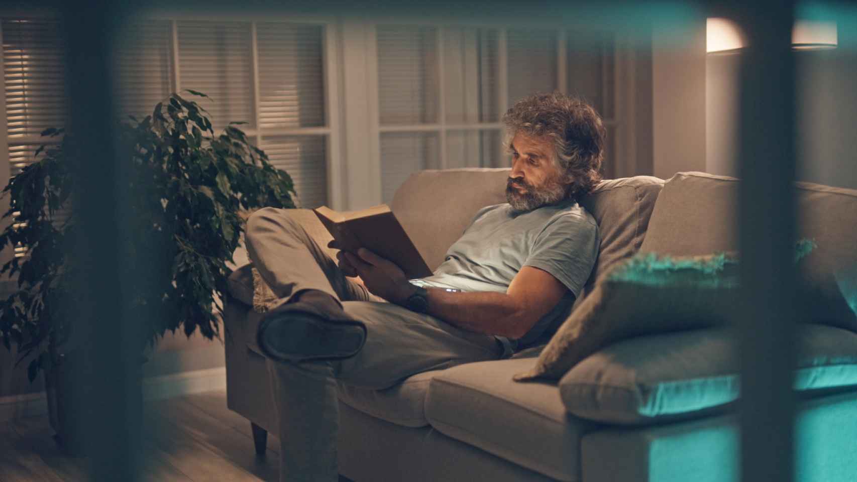 Un hombre se relaja leyendo un libro en su casa.