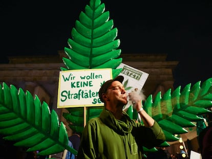 Un hombre fuma frente a un cartel que dice No queremos ser criminales en la Puerta de Brandeburgo, en Berlín, la noche del domingo al lunes.