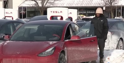 Un hombre visiblemente frustrado se encuentra cerca de un Tesla que no pudo cargarse en una estación de carga del área de Chicago el lunes.