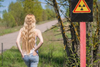 Beautiful blonde girl with beautiful long hair stands next to a sign of a  radioactive danger on the background of a forest road foto de Stock | Adobe  Stock