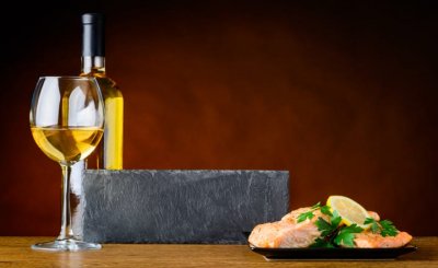 una mesa con vino blanco y un plato de pescado