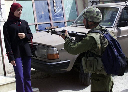 an-israeli-soldier-points-his-gun-at-a-palestinian-woman-in-the-west-bank-city-of-hebron.jpg